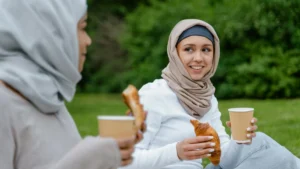 Due persone sedute all'aperto con in mano dei bicchieri di carta