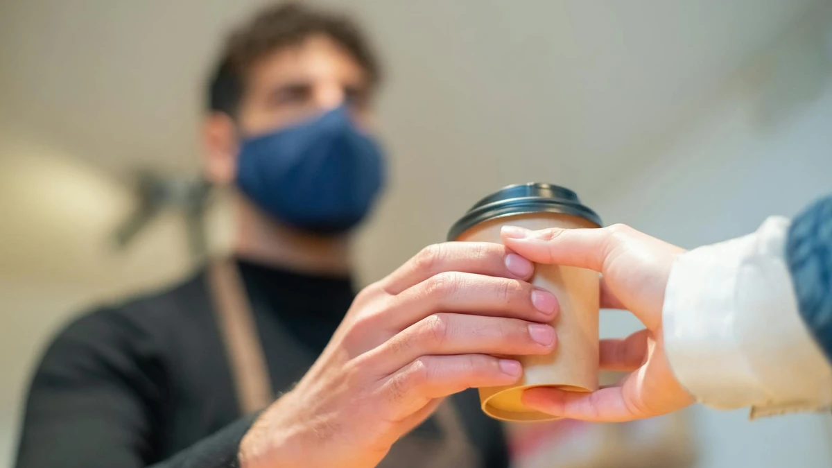 Barista serving coffee with secure disposable lid - Papacko safe packaging solutions