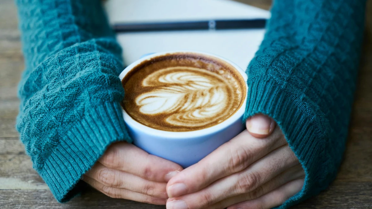 Papacko close-up of hands holding coffee cup with festive seasonal sleeve design showing printed details
