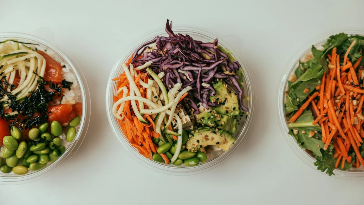 Restaurant kitchen preparing takeaway salads in kraft paper bowls