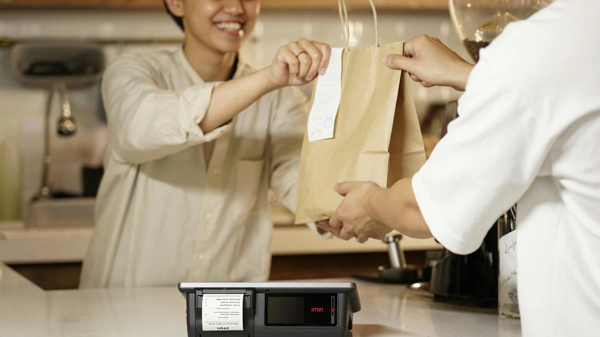 Papacko retail checkout counter with branded kraft paper bags being used for customer purchases, showing pro
